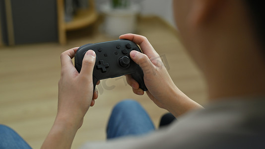 查看手持无线控制器玩视频游戏的年轻人的肩膀。