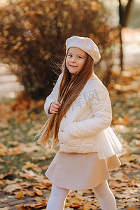 温情情绪摄影照片_一个戴着帽子的快乐女孩在秋天的公园里散步