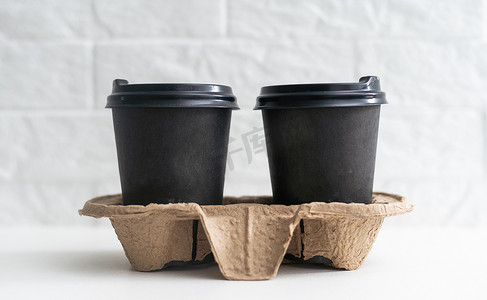 外卖纸咖啡杯放在木桌上的纸板架上，黑色背景，文字空间。