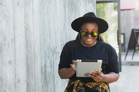 学生看电影摄影照片_美丽的非洲裔美国女性使用数字平板电脑在户外看电影或谈论视频通话或社交网络。