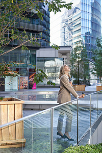 身穿米色西装的企业女性站在街外的垂直照片，上班前喝早间咖啡外卖