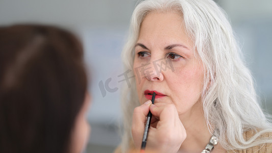 老人口红摄影照片_美容师在美容院用刷子给头发花白的老年妇女画嘴唇