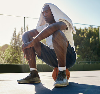 篮球、健身和一个疲惫的黑人男子在赛后坐在室外球场的球上进行运动。