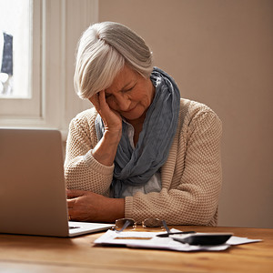 票据安全摄影照片_退休基金的忧虑……一位坐在笔记本电脑前的老年妇女看起来既紧张又担心。
