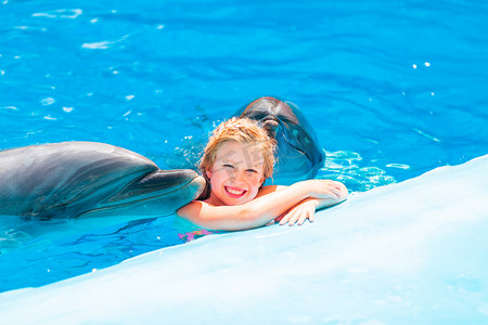 在海豚馆与海豚一起游泳的快乐小女孩