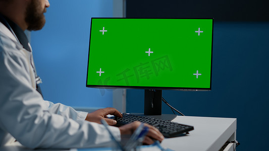 医院医生模板摄影照片_医生在带绿屏色度键显示的计算机上键入医学专业知识