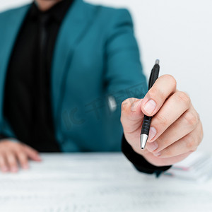身穿蓝色西装的男模特坐在白桌旁，用笔指着重要信息。