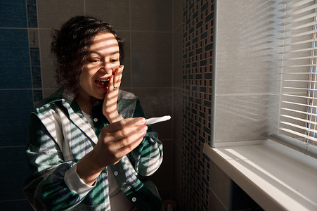 飘舞喷墨摄影照片_中年多种族女性在进行阳性喷墨妊娠试验时感到幸福