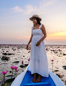海莉摄影照片_泰国乌隆他尼的红莲海 Kumphawapi 满是粉红色的花朵，亚洲女性在一艘船上。