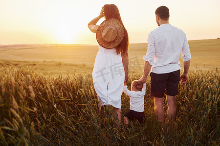 母亲和父亲带着他们的儿子在夏天阳光明媚的日子里在田野上度过空闲时间。