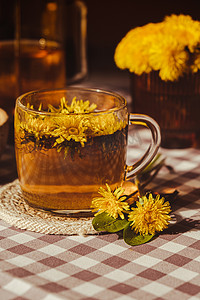 蒲公英茶摄影照片_蒲公英花健康茶在玻璃茶壶和玻璃杯在桌上。