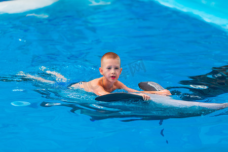 在海豚馆与海豚一起游泳的快乐小男孩