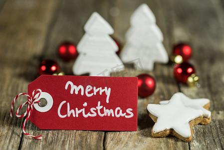 手写快乐摄影照片_与星饼干和装饰品的木桌上的手写的圣诞快乐问候的标签