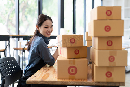 中小企业企业家小企业企业家在线销售创意，快乐年轻的亚洲企业主在家里用电脑和盒子工作，向客户交付中小企业采购包装盒
