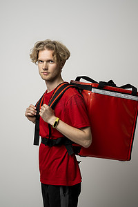 身穿红色制服、红色背景上带有热袋的年轻信使的侧视图，文字空间。