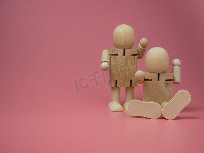 说话的娃娃摄影照片_2 个木娃娃坐着和站着，在粉红色的背景上做着说话的手势。