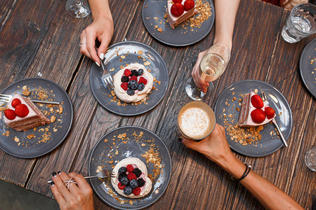 单身派对，女孩们在木桌上拿着饮料和甜蛋糕，上面放着夏季浆果。