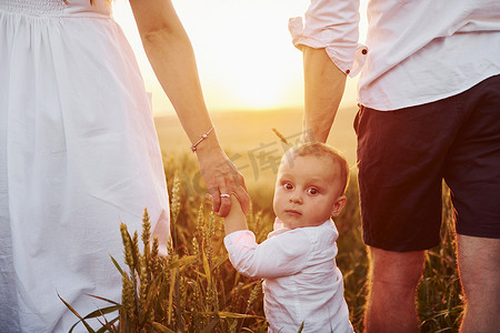 母亲背儿子摄影照片_母亲和父亲带着他们的儿子在夏天阳光明媚的日子里在田野上度过空闲时间。