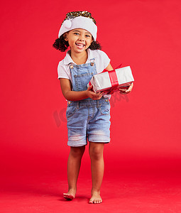 肖像、圣诞节和礼物与一个黑人女孩在工作室的红色背景中庆祝节日。