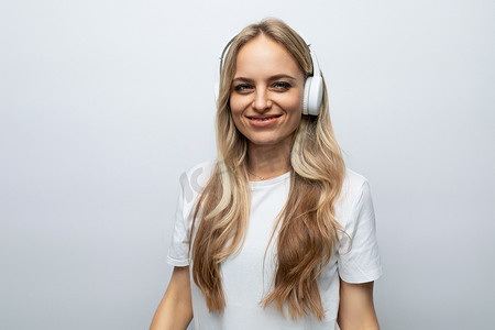戴着白色耳机的快乐年轻女性在白色背景下收听播客