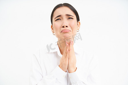 女脸手摄影照片_心烦意乱的亚洲女人带着绝望和悲伤的脸抬头，向上帝抱怨，站在白色背景上