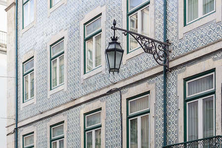 古老的葡萄牙建筑，覆盖着蓝色图案的 azulejo 瓷砖，墙上挂着锻铁灯笼