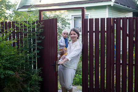 带着婴儿的好奇女人打开栅栏门，看着相机