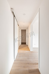 在搬家前或装修后，白色走廊有通向明亮房间的入口，空荡荡的公寓里有滑动门。