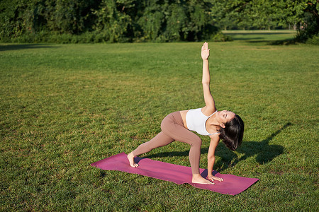 亚洲年轻女性伸展运动、在橡胶垫上做瑜伽、在公园锻炼、在新鲜空气中进行有意识的训练