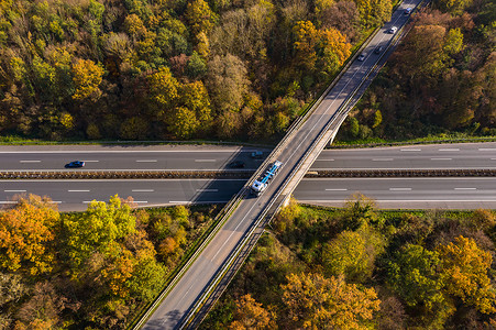 高速公路上一座桥的鸟瞰图，穿过秋天的森林，交通繁忙