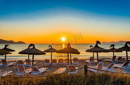 日落时带椅子和太阳伞的海滩，假日旅游概念