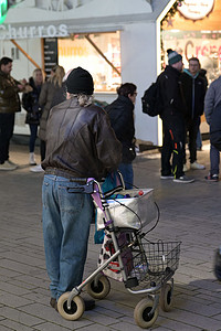 一个身穿黑色皮夹克的人在德国杜塞尔多夫的德国圣诞市场上推着一个滚动的步行者