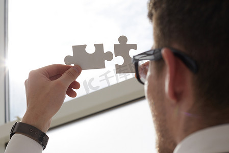 商人双手连接代表两家公司合并或合资、合伙、兼并和收购概念的拼图。