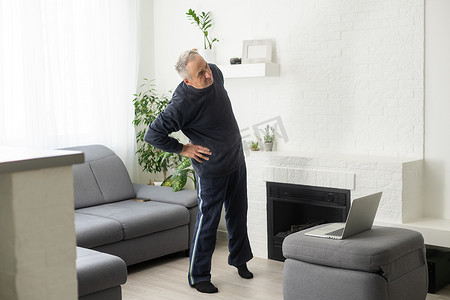 活跃的老人在家锻炼期间观看在线健身课程。