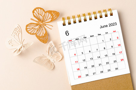 年度计划摄影照片_2023 年 6 月的台历，供组织者在黄色背景上进行计划和提醒以及蝴蝶结。