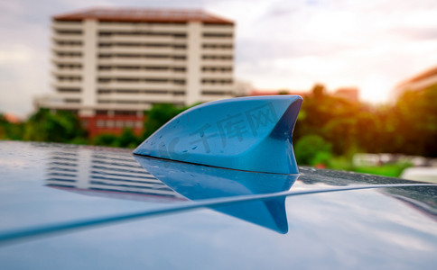 汽车定位摄影照片_蓝色屋顶上的特写汽车鱼翅无线天线。 