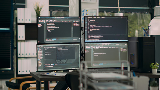 显示器在空的 IT 机构办公桌上显示解析代码与计算机