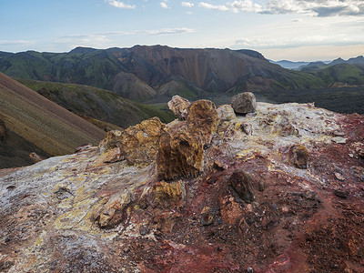 气孔摄影照片_Brennisteinsalda 山脚下的彩色流纹岩红色和橙色喷气孔，可欣赏兰德曼纳劳卡全景。