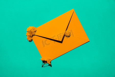 美丽的黄色小洋甘菊雏菊花在绿色背景的邮政橙色信封上，空白的纸条复制空间用于文本，春天，节日贺卡。