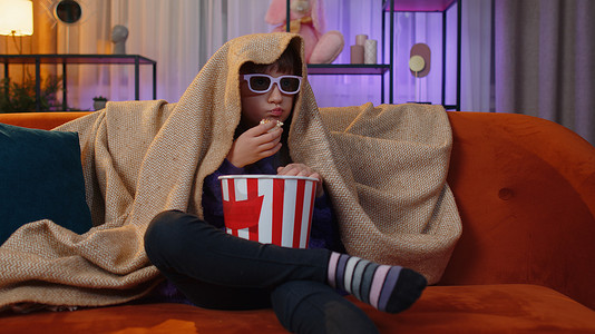 Oreteen 女孩吃爆米花，在家里的沙发上看有趣的电视连续剧、体育游戏在线内容