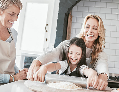 .母亲、祖母和孩子一起在家庭厨房里用擀面杖做糕点、馅饼或比萨饼。