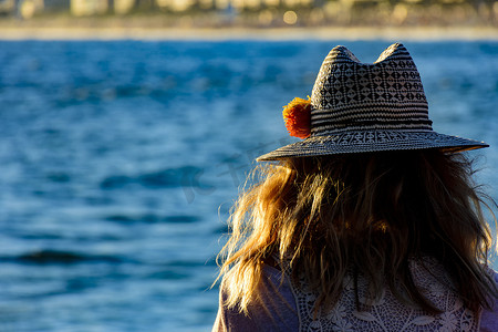 午后花摄影照片_看着伊帕内玛海滩的戴花帽的女人