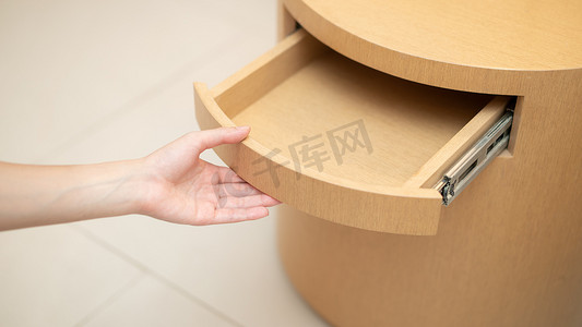 女人用手打开木桌上的抽屉。