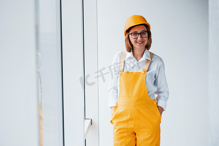 身穿黄色制服、头戴安全帽的女工或工程师站在室内