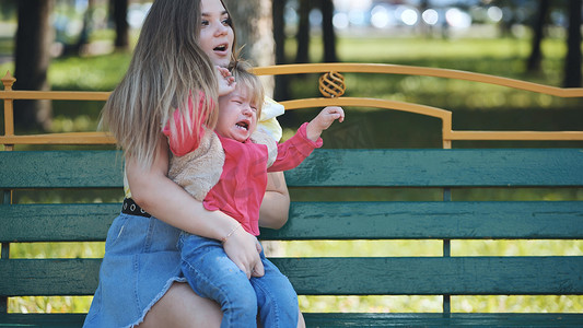 一位母亲在公园里安抚哭闹的婴儿。