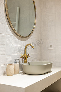 陶瓷业摄影照片_现代浴室的白色光滑大理石台面上的椭圆形时尚水槽。