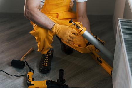 黄色制服的杂工使用特殊工具在室内使用热电池工作。