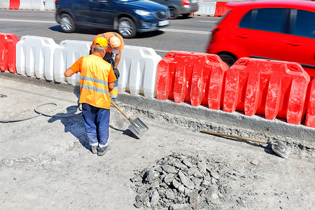 道路工人在道路维修期间拆除旧混凝土并铲平工作区域。