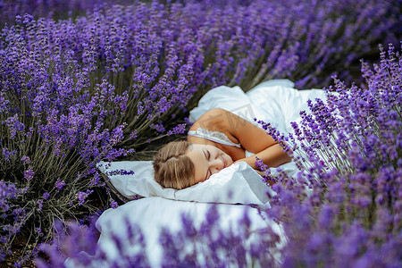 一位中年妇女躺在薰衣草花田里享受香熏。