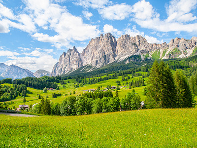 意大利多洛米蒂山，科尔蒂纳丹佩佐上方的 Pomagagnon 山的岩石山脊，绿草如茵，蓝天白云